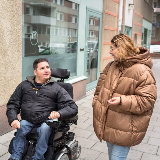 Bild på en assistansberättigad och personlig assistent som är på promenad och talar med varandra