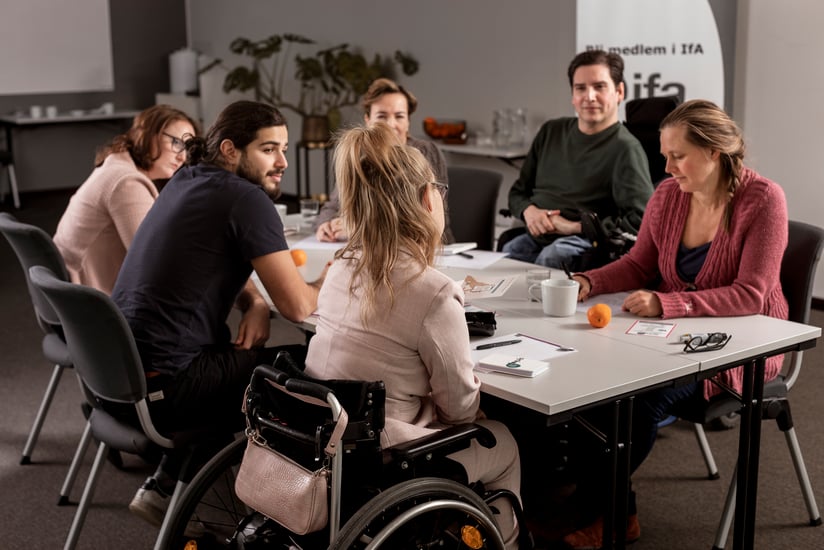 en grupp människor sitter vid ett bord och diskuterar