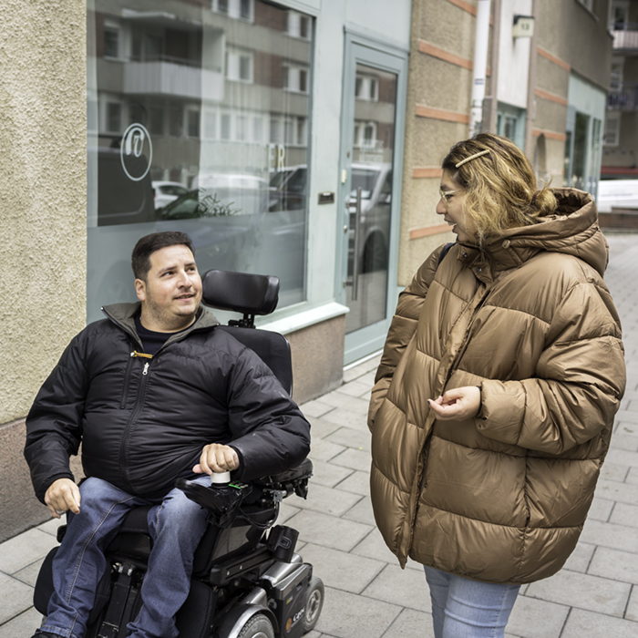 Bild på en assistansberättigad och personlig assistent som är på promenad och talar med varandra